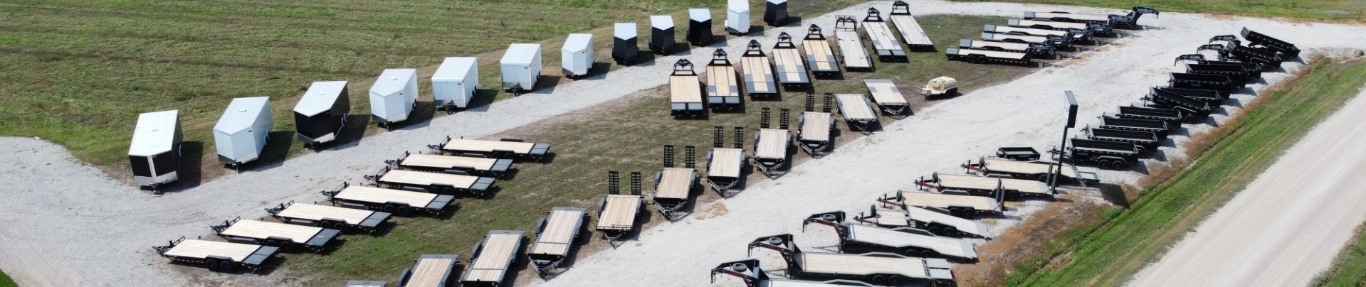 Aerial view of a trailer sales lot with enclosed, flatbed, and gooseneck trailers on display.